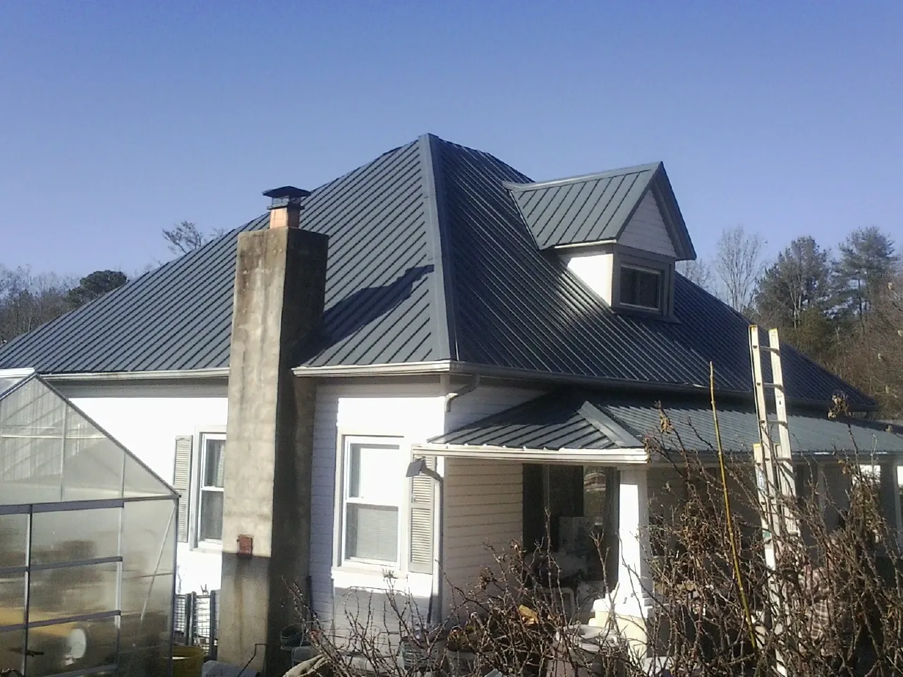 Dark blue standing seam metal roof on a white farmhouse with dormer — Slate & Tile Roof Repair by Roofing Brothers in Medfield