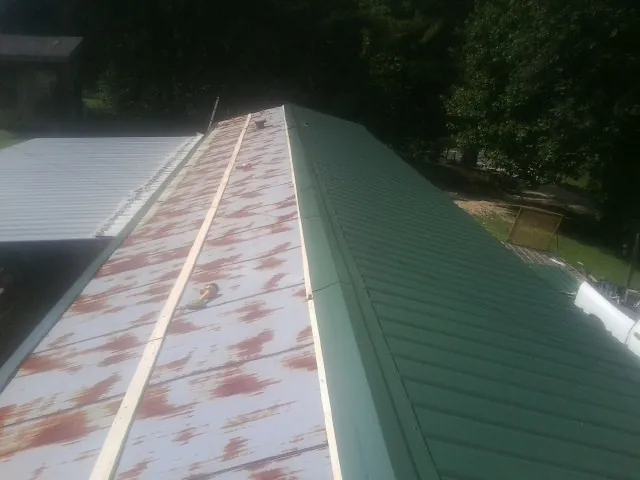 Old rusted panels beside newly installed green metal roofing — Wind Damage Roof Repair by Roofing Brothers in Medfield