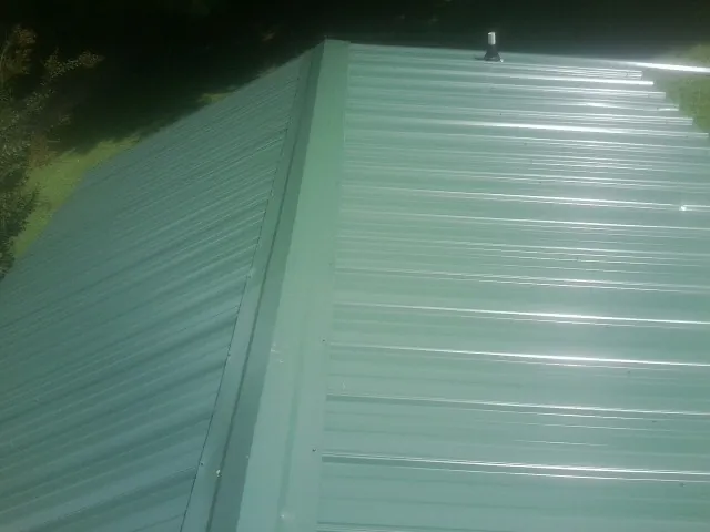 New green metal panels meeting at the ridge of a roof — Flat Roof Repair work by our crew in Medfield
