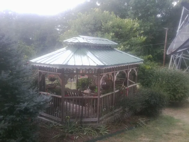 Green metal roof on a backyard gazebo surrounded by garden beds in Medfield