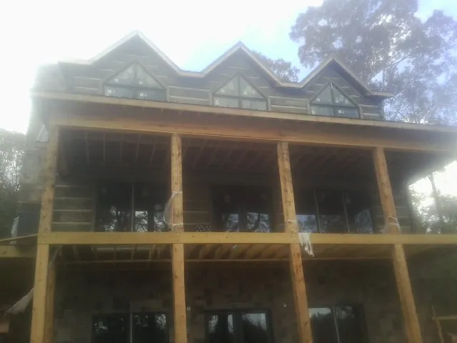 Dormers and porch framing on a large log home under construction — Roof Coating work by our crew in Medfield
