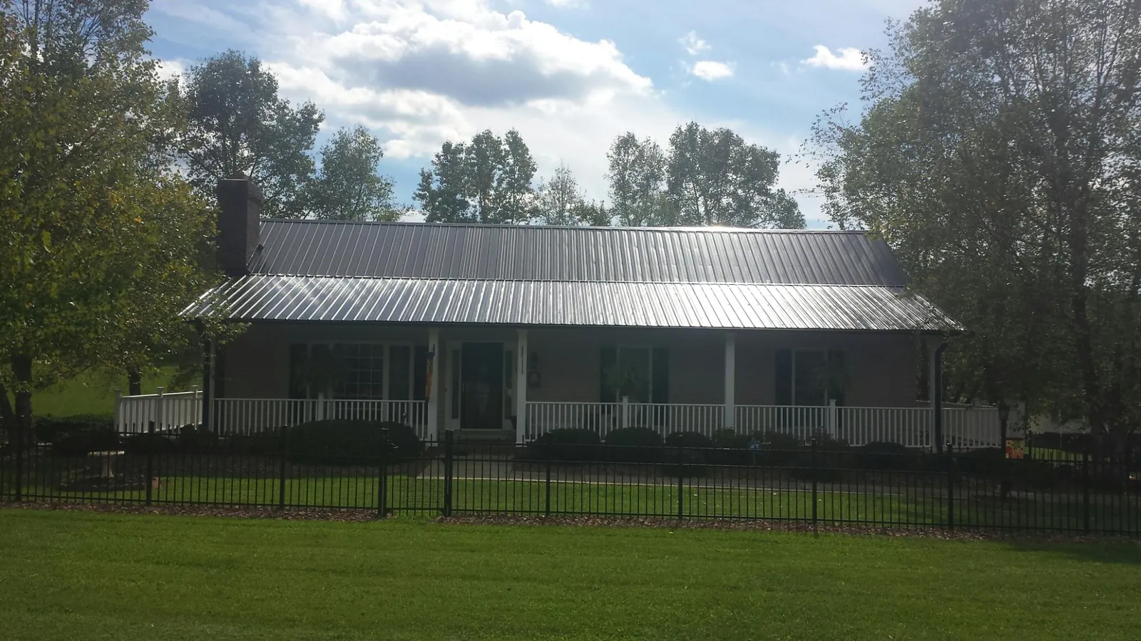 Gray metal roof on a brick ranch with a full width front porch — Gutter Guard Installation work by our crew in Medfield