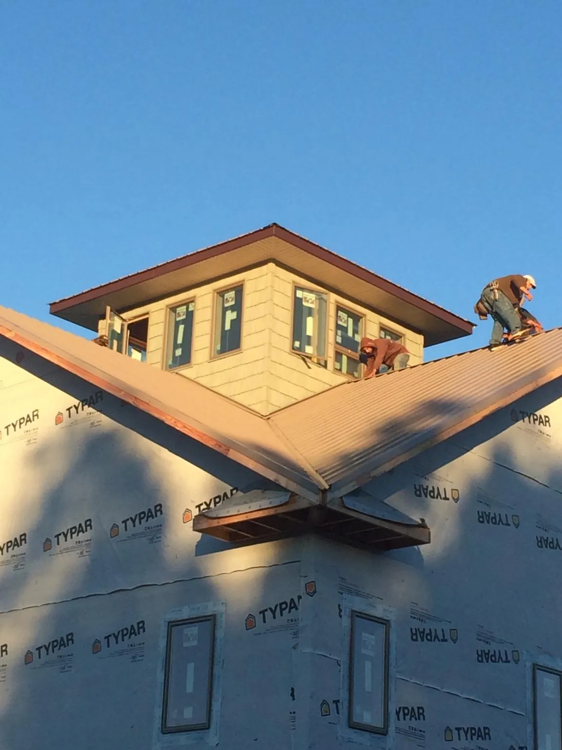 Roofers working around a rooftop cupola on a new metal roof at sunset — Roof Waterproofing in Medfield by Roofing Brothers